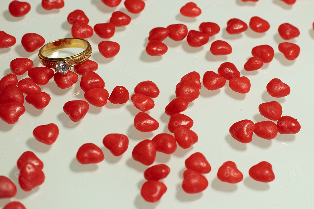 Uma aliança de casamento com vários pequenos corações na mesa branca