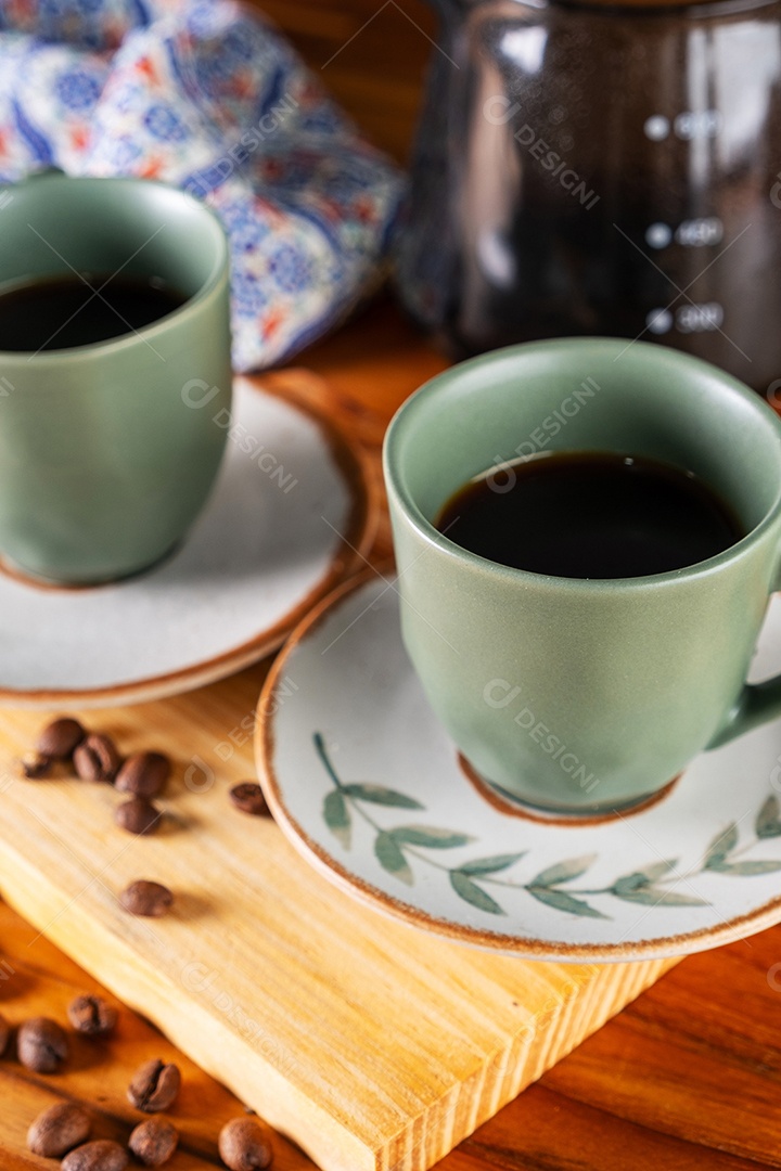 Duas xícaras de café e coador usado no fundo