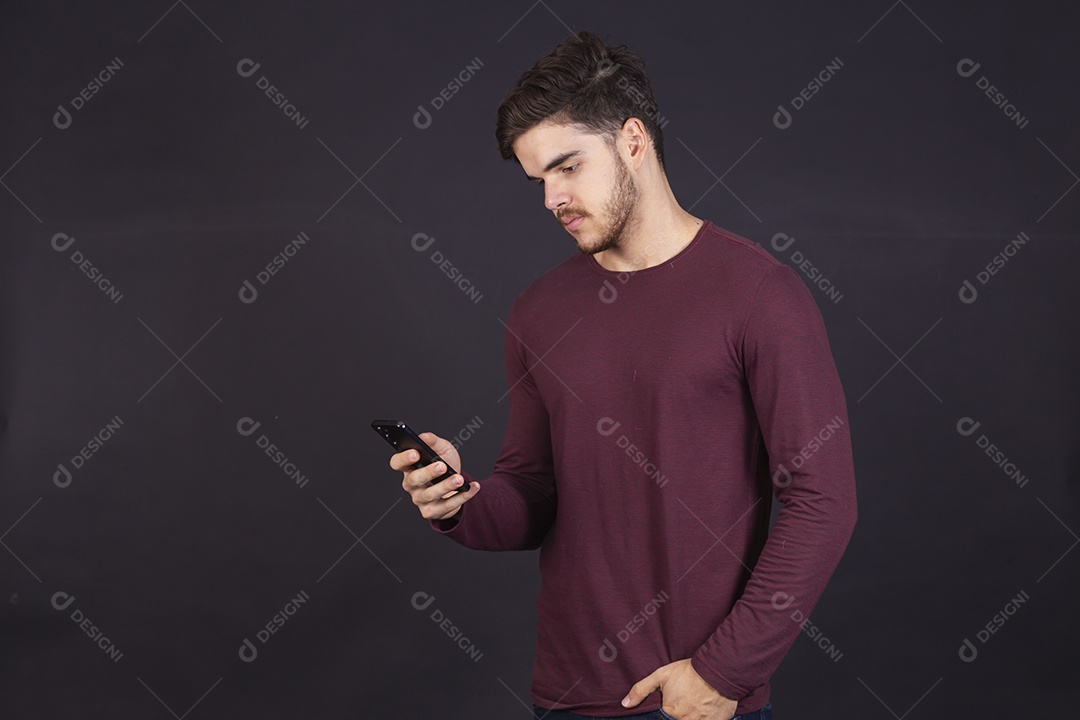 Homem jovem sobre fundo isolado mexendo no seu celular