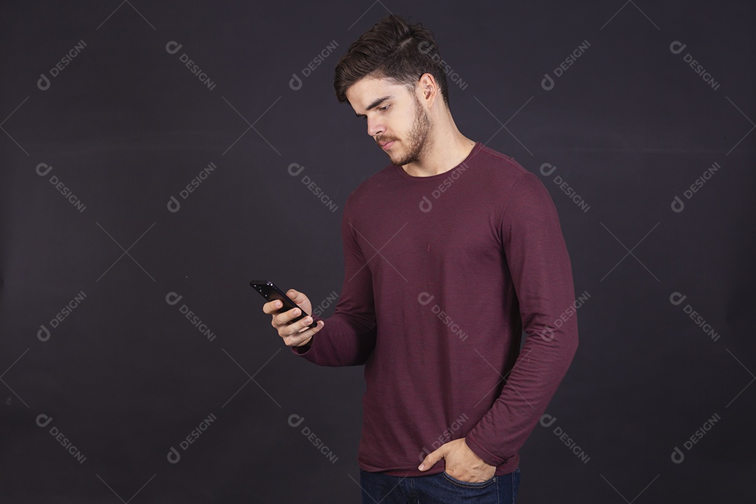 Homem jovem sobre fundo isolado mexendo no seu celular
