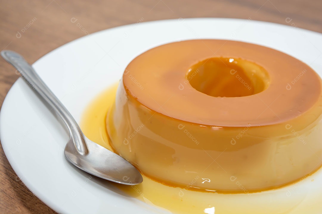 Pudim de leite em uma mesa de madeira com colher metálica