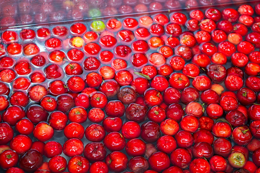 Lavando acerola na pia.