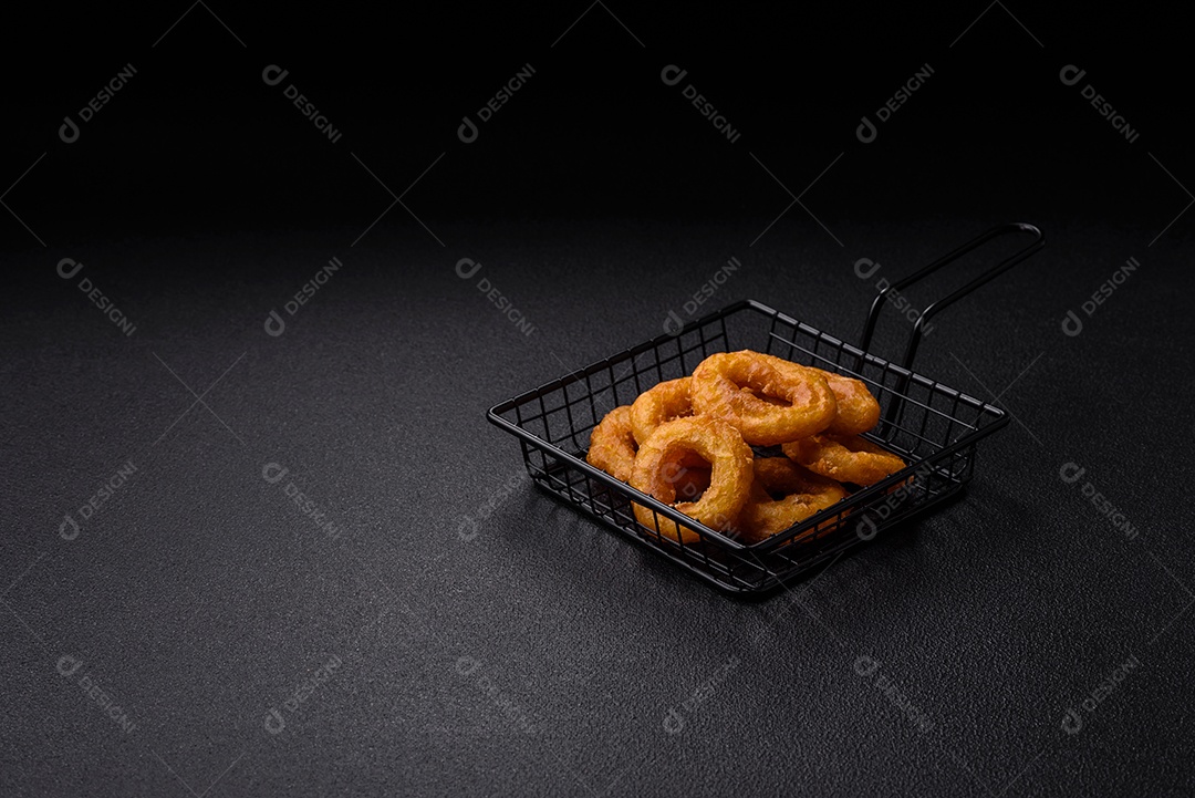 Deliciosas lulas nutritivas ou anéis de cebola fritos com sal e especiarias sobre um fundo escuro de concreto