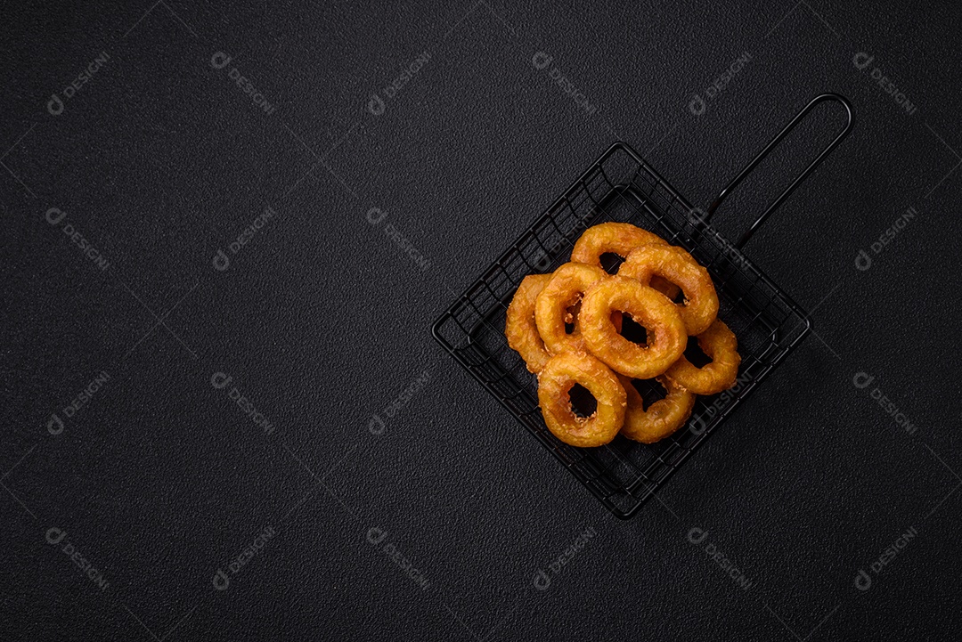 Deliciosas lulas nutritivas ou anéis de cebola fritos com sal e especiarias sobre um fundo escuro de concreto