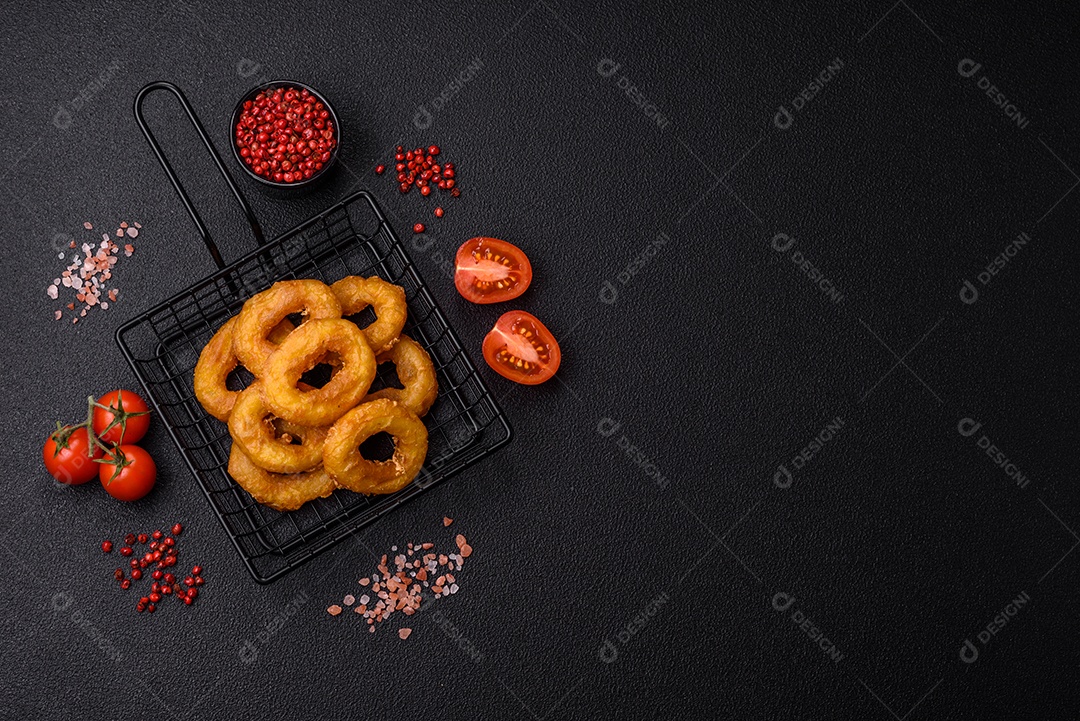 Deliciosas lulas nutritivas ou anéis de cebola fritos com sal e especiarias sobre um fundo escuro de concreto