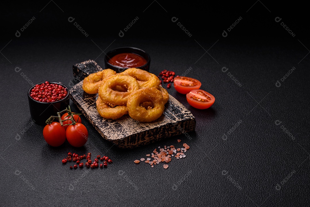 Deliciosas lulas nutritivas ou anéis de cebola fritos com sal e especiarias sobre um fundo escuro de concreto