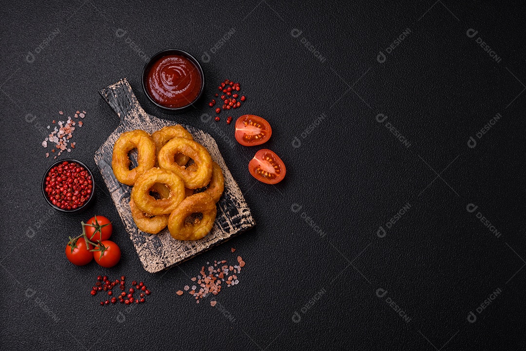 Deliciosas lulas nutritivas ou anéis de cebola fritos com sal e especiarias sobre um fundo escuro de concreto