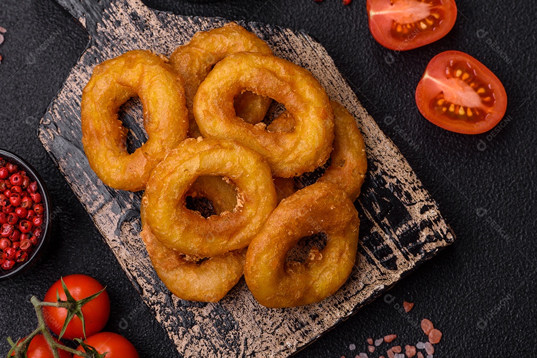 Deliciosas lulas nutritivas ou anéis de cebola fritos com sal e especiarias sobre um fundo escuro de concreto