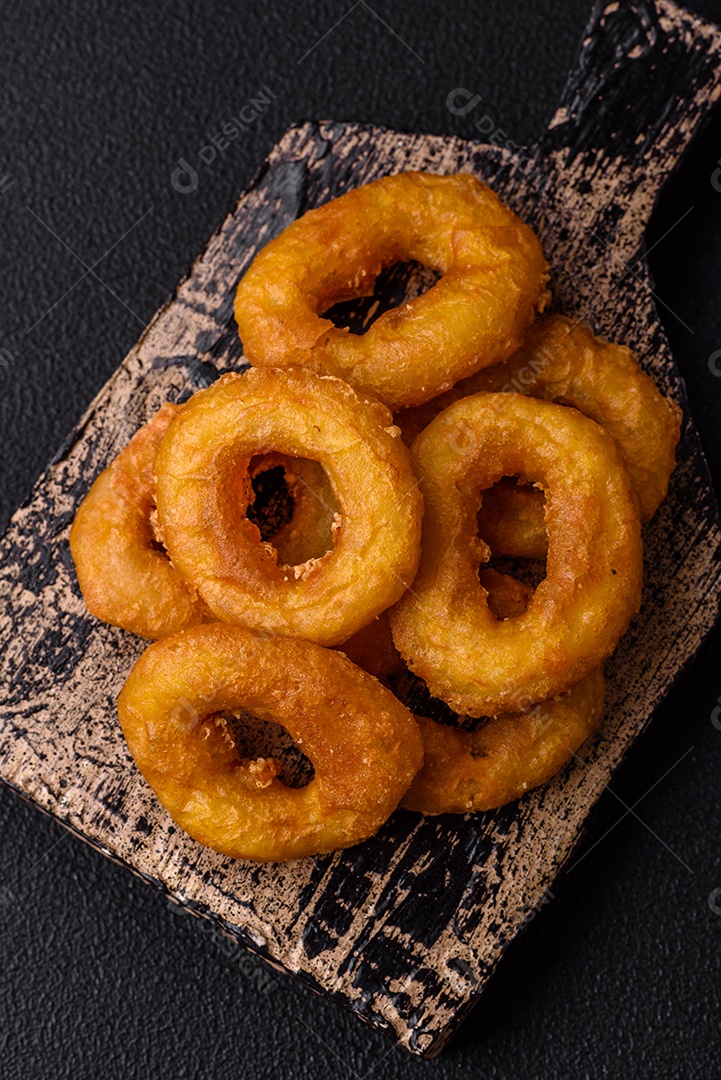 Deliciosas lulas nutritivas ou anéis de cebola fritos com sal e especiarias sobre um fundo escuro de concreto