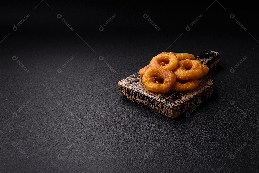 Deliciosas lulas nutritivas ou anéis de cebola fritos com sal e especiarias sobre um fundo escuro de concreto