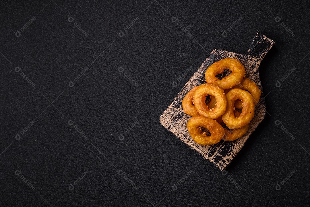 Deliciosas lulas nutritivas ou anéis de cebola fritos com sal e especiarias sobre um fundo escuro de concreto