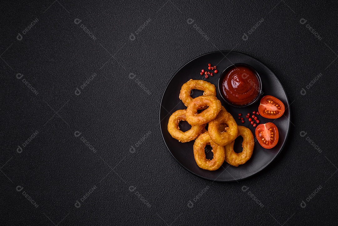 Deliciosas lulas nutritivas ou anéis de cebola fritos com sal e especiarias sobre um fundo escuro de concreto