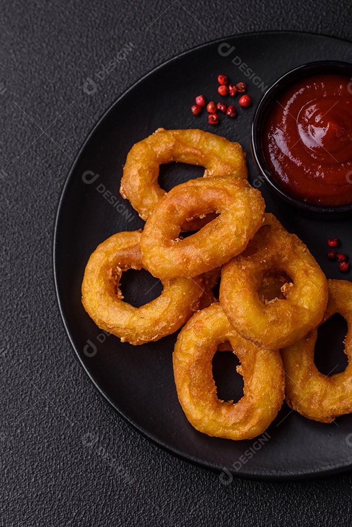 Deliciosas lulas nutritivas ou anéis de cebola fritos com sal e especiarias sobre um fundo escuro de concreto