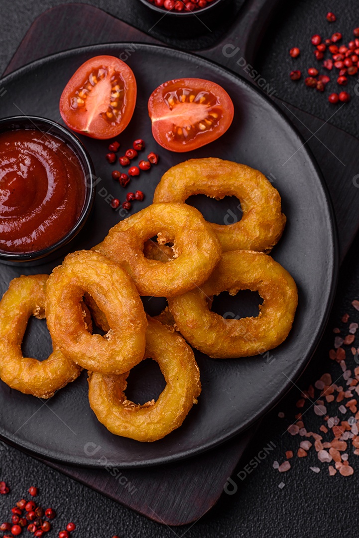 Deliciosas lulas nutritivas ou anéis de cebola fritos com sal e especiarias sobre um fundo escuro de concreto