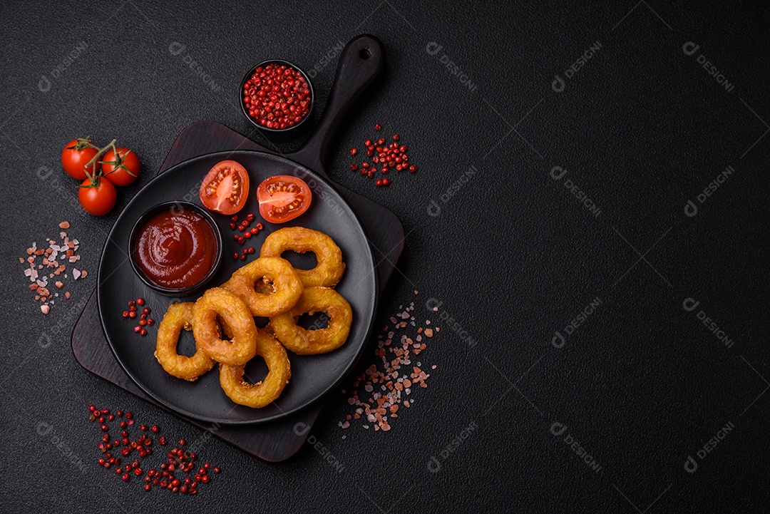 Deliciosas lulas nutritivas ou anéis de cebola fritos com sal e especiarias sobre um fundo escuro de concreto