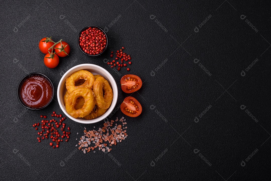 Deliciosas lulas nutritivas ou anéis de cebola fritos com sal e especiarias sobre um fundo escuro de concreto