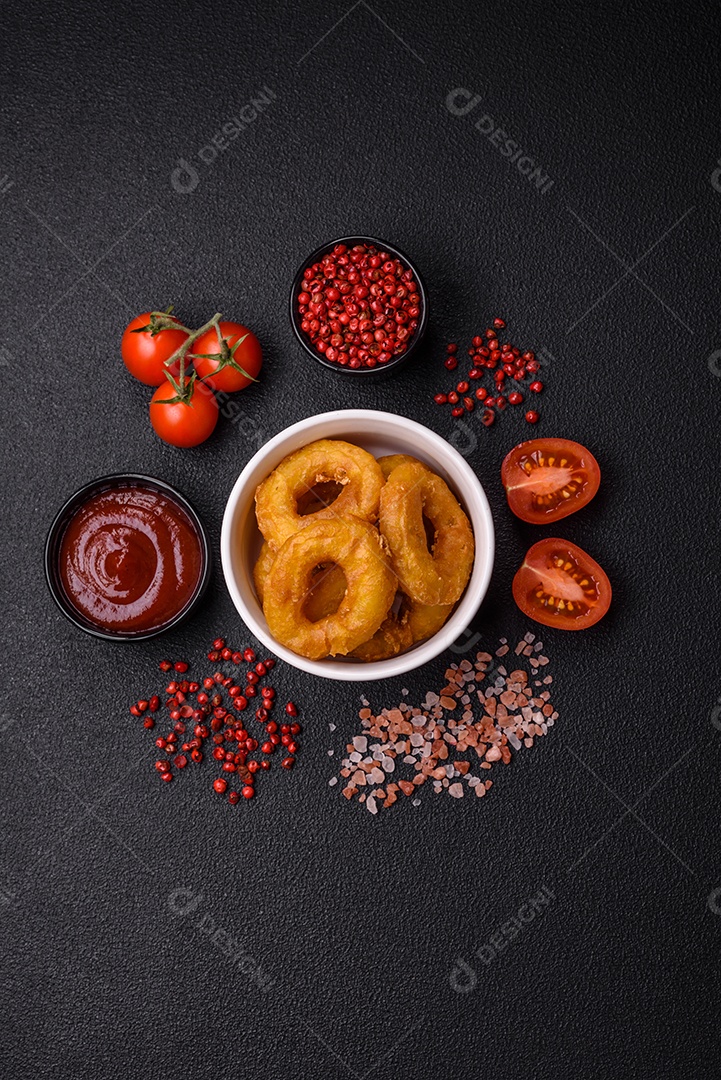 Deliciosas lulas nutritivas ou anéis de cebola fritos com sal e especiarias sobre um fundo escuro de concreto