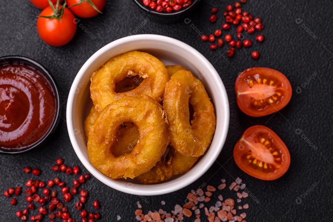 Deliciosas lulas nutritivas ou anéis de cebola fritos com sal e especiarias sobre um fundo escuro de concreto