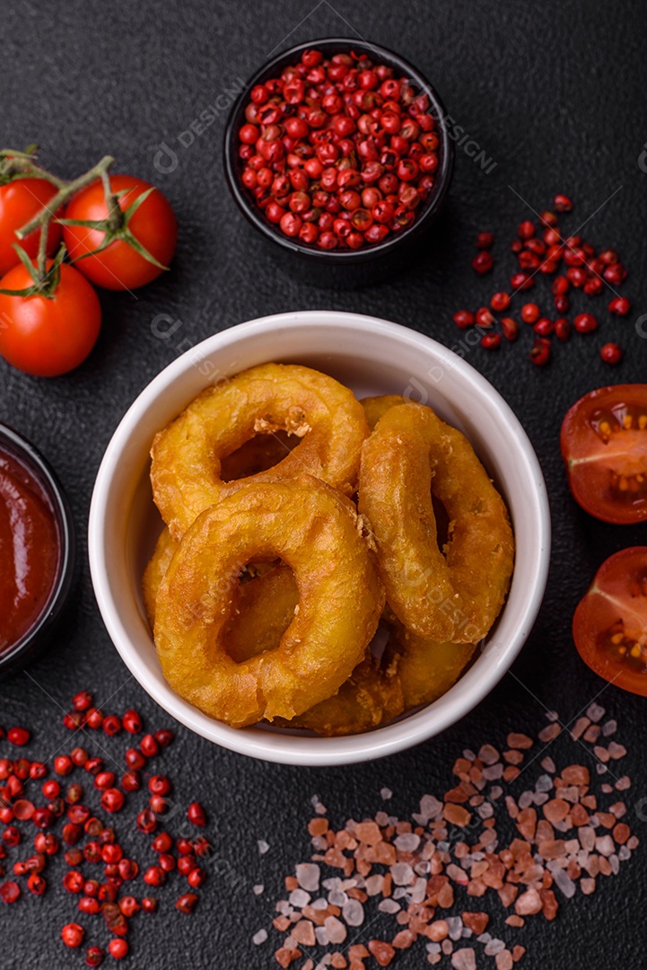 Deliciosas lulas nutritivas ou anéis de cebola fritos com sal e especiarias sobre um fundo escuro de concreto