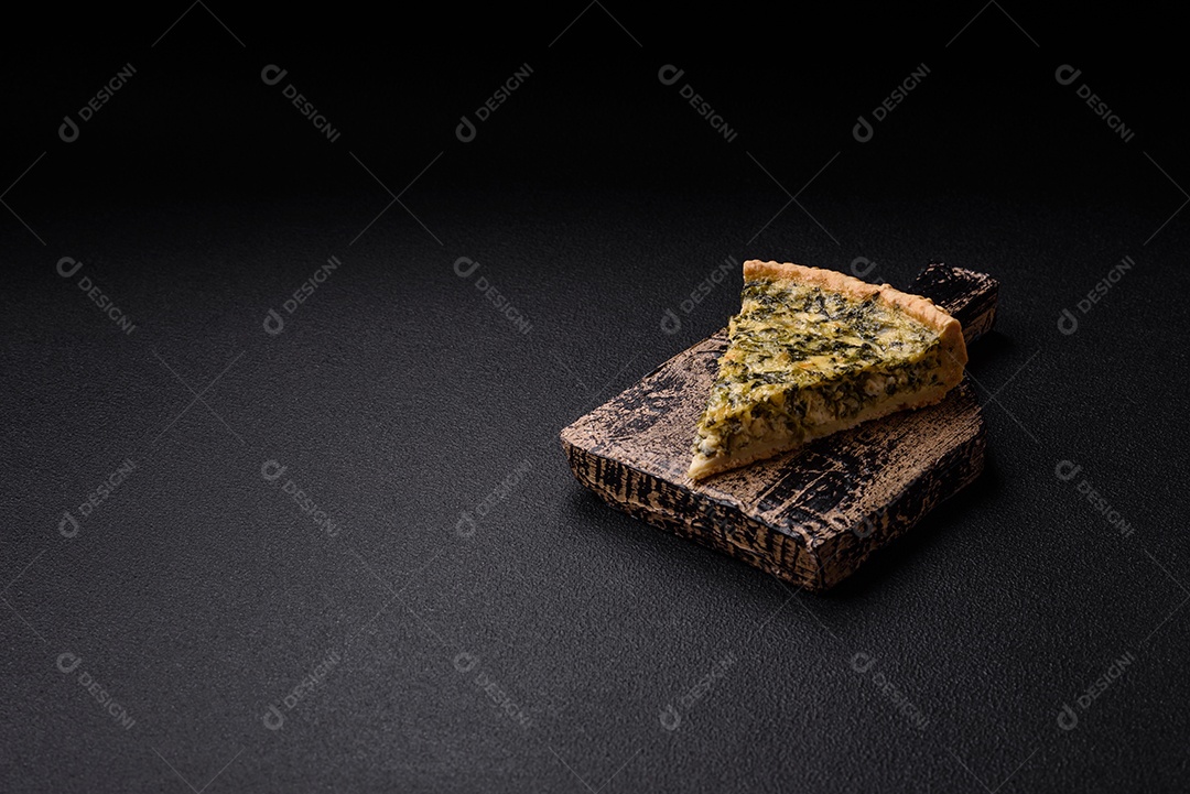 Deliciosa quiche crocante cortada em fatias com queijo, brócolis, tomate, sal, especiarias e ervas sobre um fundo escuro de concreto