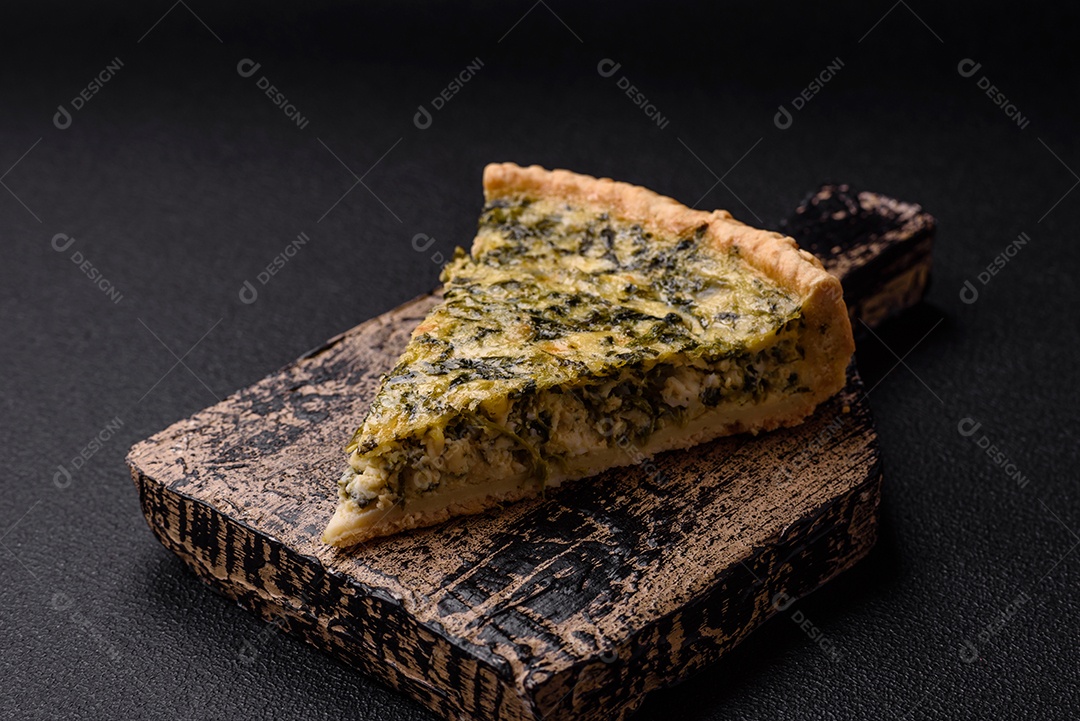 Deliciosa quiche crocante cortada em fatias com queijo, brócolis, tomate, sal, especiarias e ervas sobre um fundo escuro de concreto