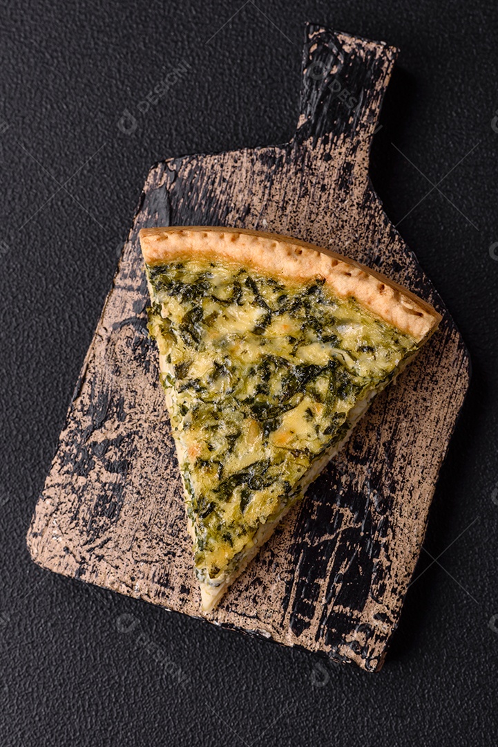 Deliciosa quiche crocante cortada em fatias com queijo, brócolis, tomate, sal, especiarias e ervas sobre um fundo escuro de concreto