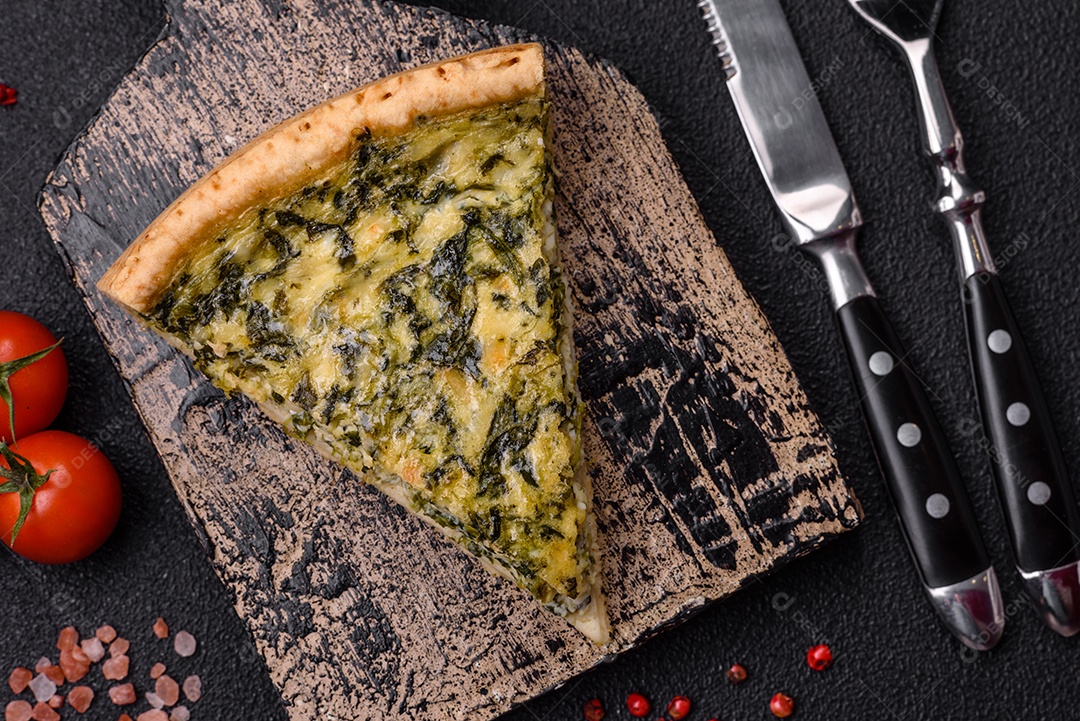 Deliciosa quiche crocante cortada em fatias com queijo, brócolis, tomate, sal, especiarias e ervas sobre um fundo escuro de concreto