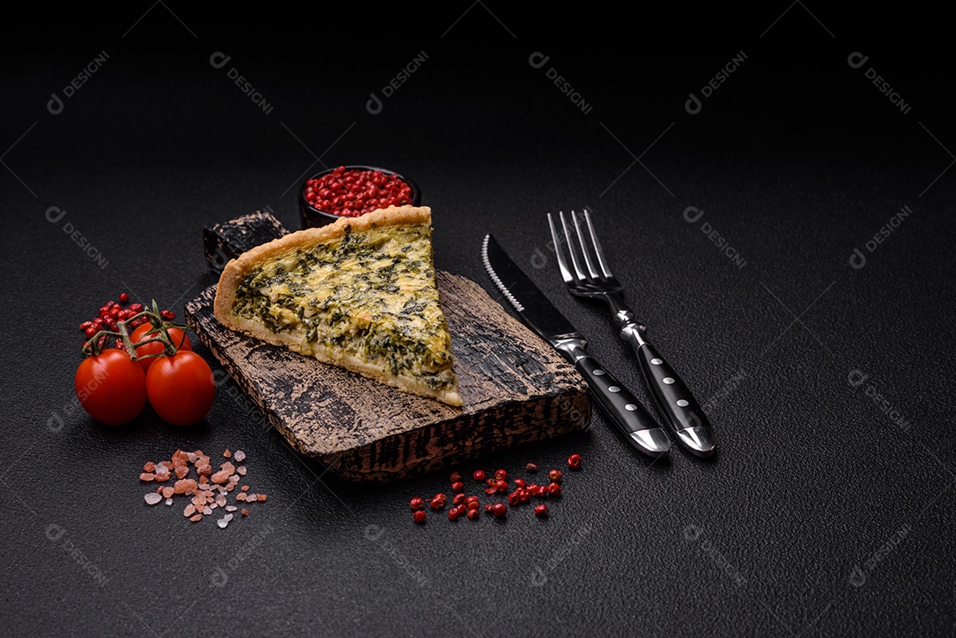 Deliciosa quiche crocante cortada em fatias com queijo, brócolis, tomate, sal, especiarias e ervas sobre um fundo escuro de concreto