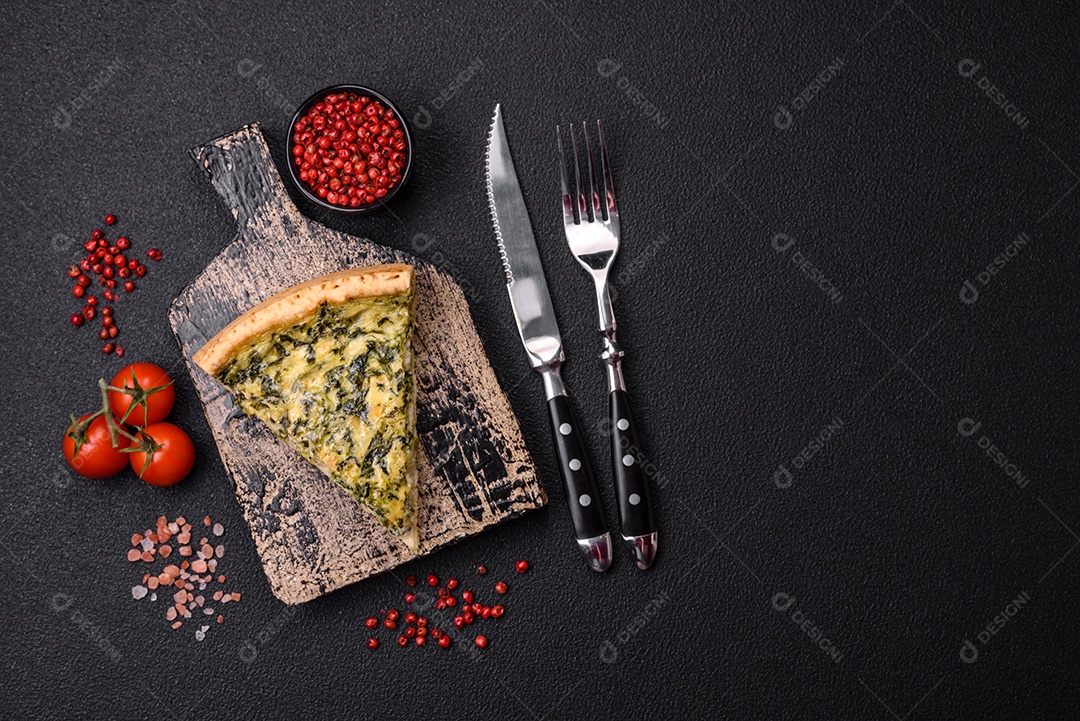 Deliciosa quiche crocante cortada em fatias com queijo, brócolis, tomate, sal, especiarias e ervas sobre um fundo escuro de concreto