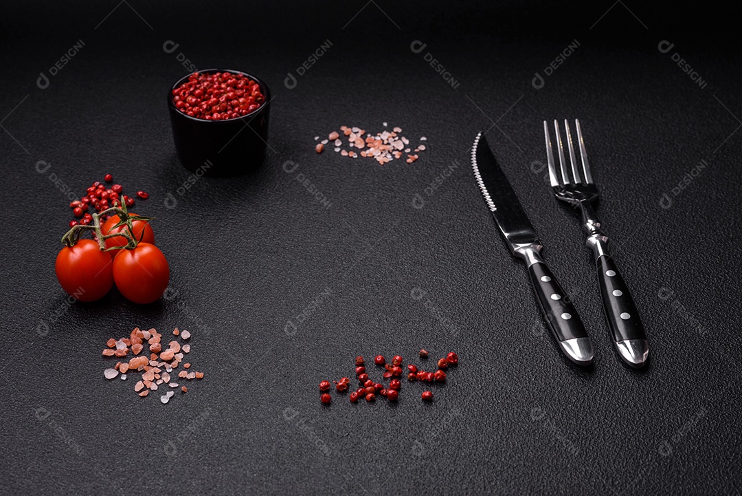 Sal, pimenta da Jamaica, tomate cereja em um fundo escuro de concreto. Ingredientes para cozinhar em casa