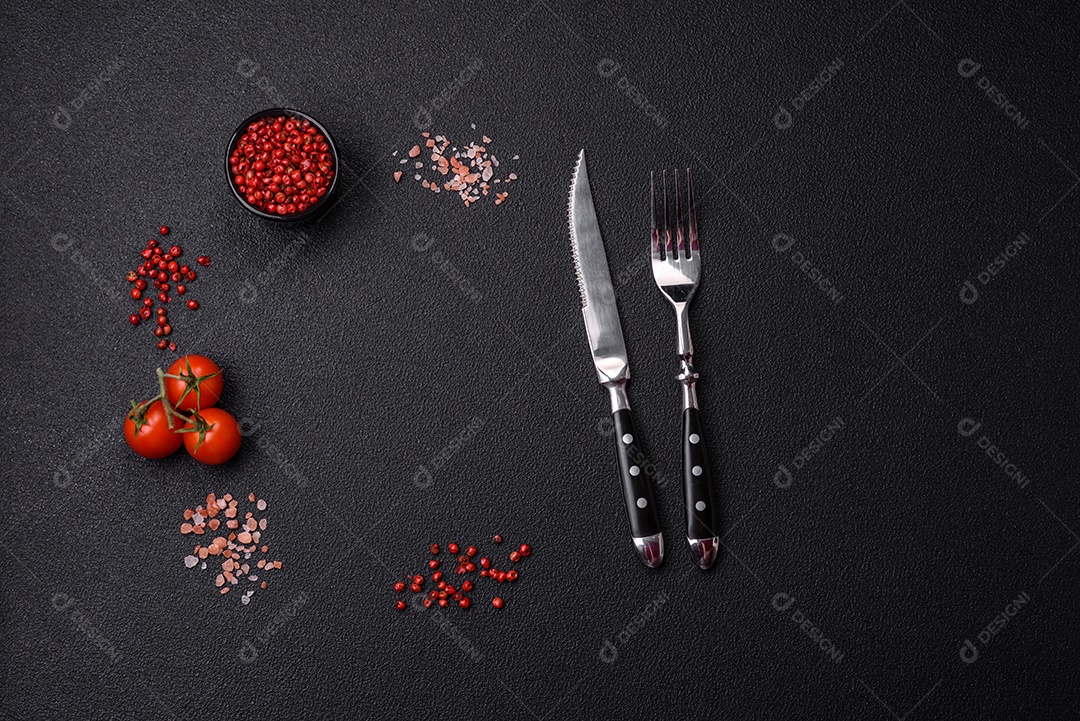 Sal, pimenta da Jamaica, tomate cereja em um fundo escuro de concreto. Ingredientes para cozinhar em casa