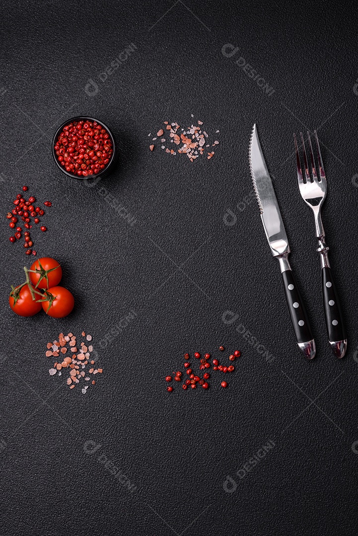 Sal, pimenta da Jamaica, tomate cereja em um fundo escuro de concreto. Ingredientes para cozinhar em casa