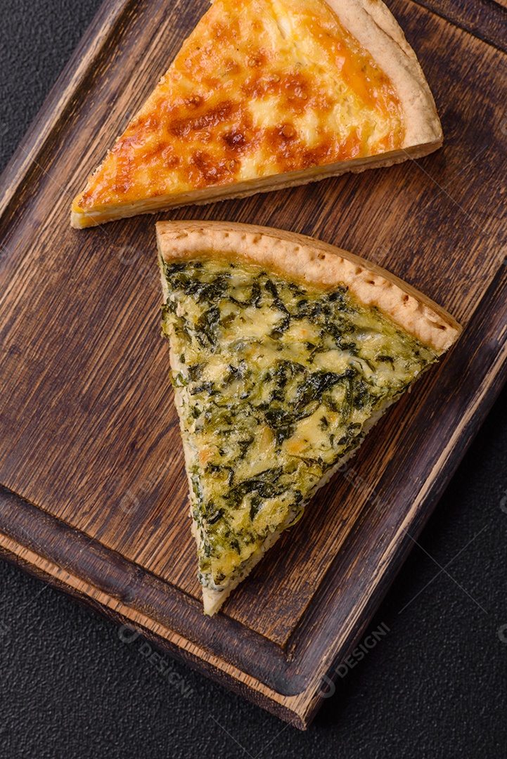 Deliciosa quiche crocante cortada em fatias com queijo, brócolis, tomate, sal, especiarias e ervas sobre um fundo escuro de concreto