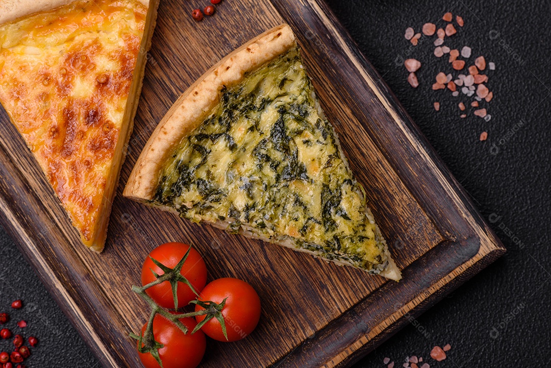 Deliciosa quiche crocante cortada em fatias com queijo, brócolis, tomate, sal, especiarias e ervas sobre um fundo escuro de concreto