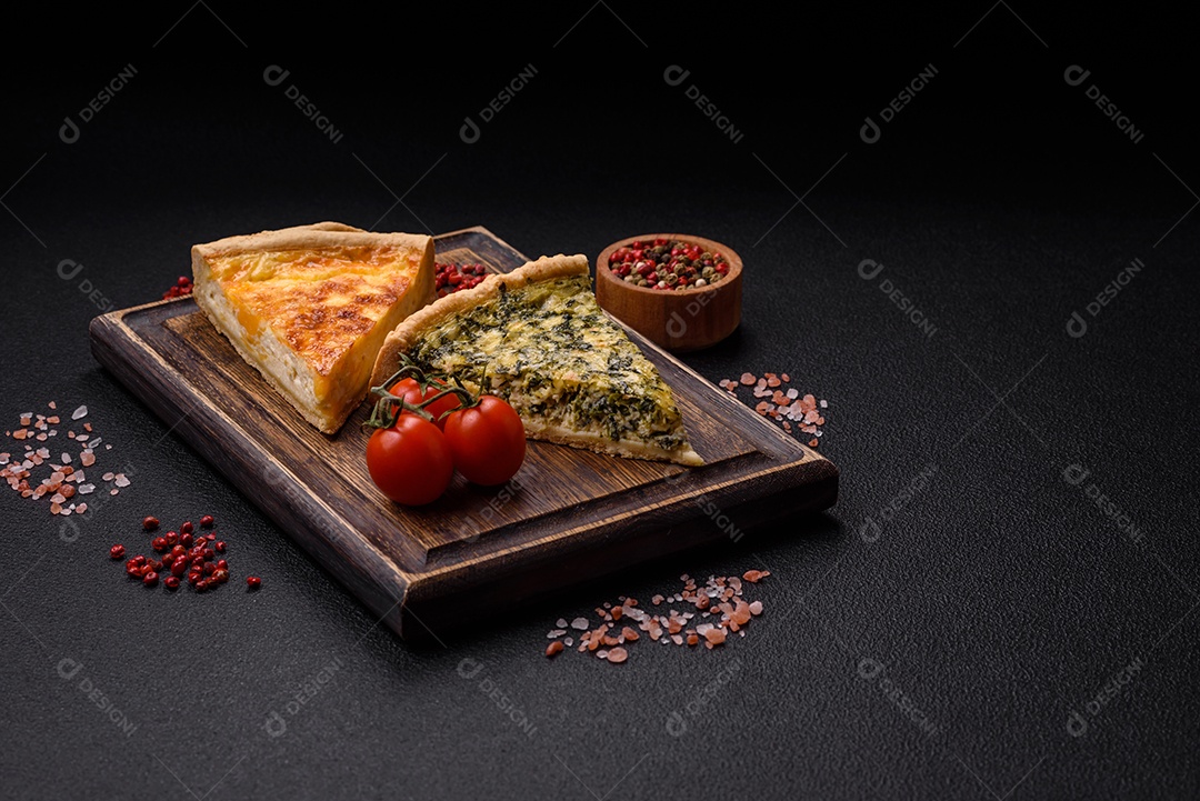 Deliciosa quiche crocante cortada em fatias com queijo, brócolis, tomate, sal, especiarias e ervas sobre um fundo escuro de concreto