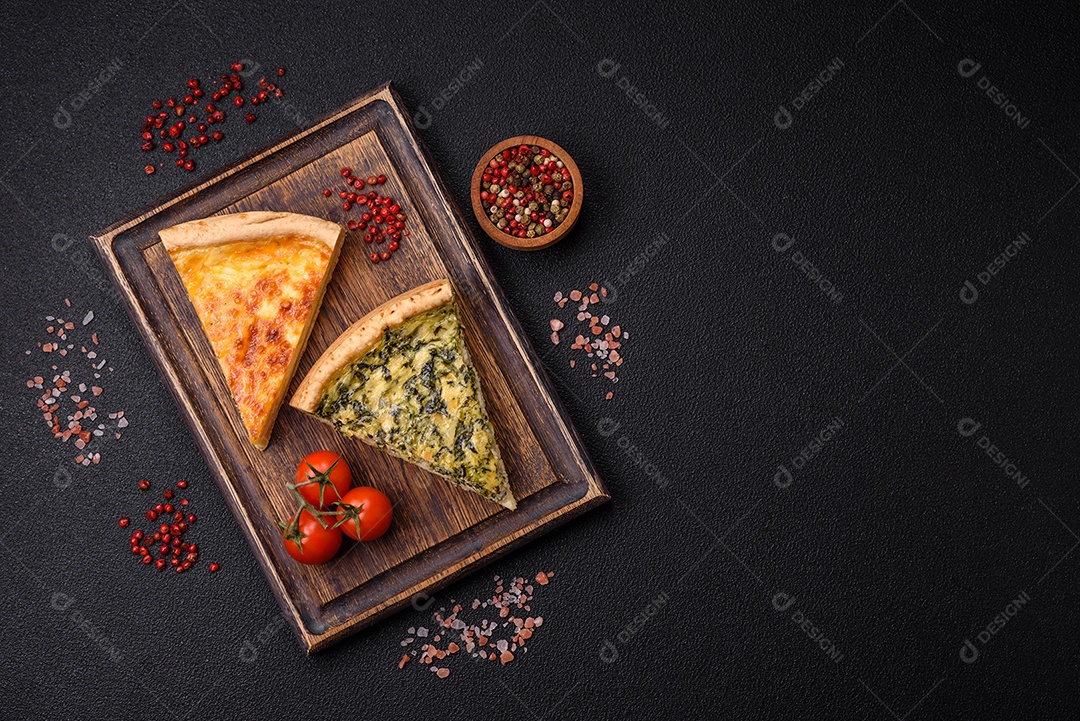 Deliciosa quiche crocante cortada em fatias com queijo, brócolis, tomate, sal, especiarias e ervas sobre um fundo escuro de concreto