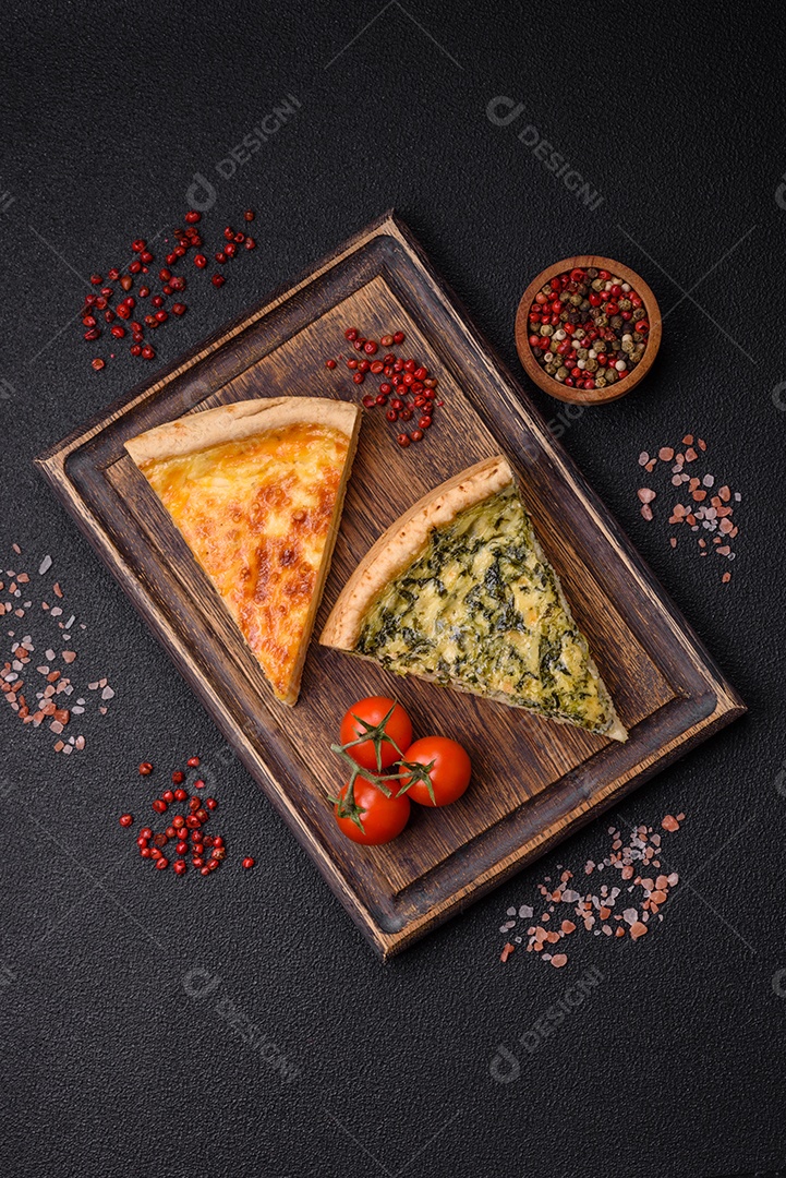 Deliciosa quiche crocante cortada em fatias com queijo, brócolis, tomate, sal, especiarias e ervas sobre um fundo escuro de concreto