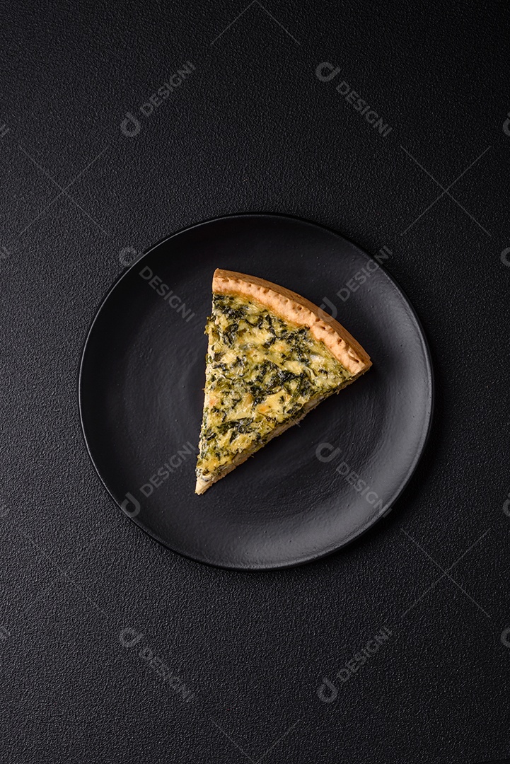 Deliciosa quiche crocante cortada em fatias com queijo, brócolis, tomate, sal, especiarias e ervas sobre um fundo escuro de concreto