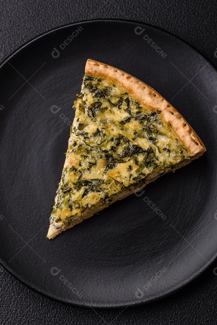 Deliciosa quiche crocante cortada em fatias com queijo, brócolis, tomate, sal, especiarias e ervas sobre um fundo escuro de concreto