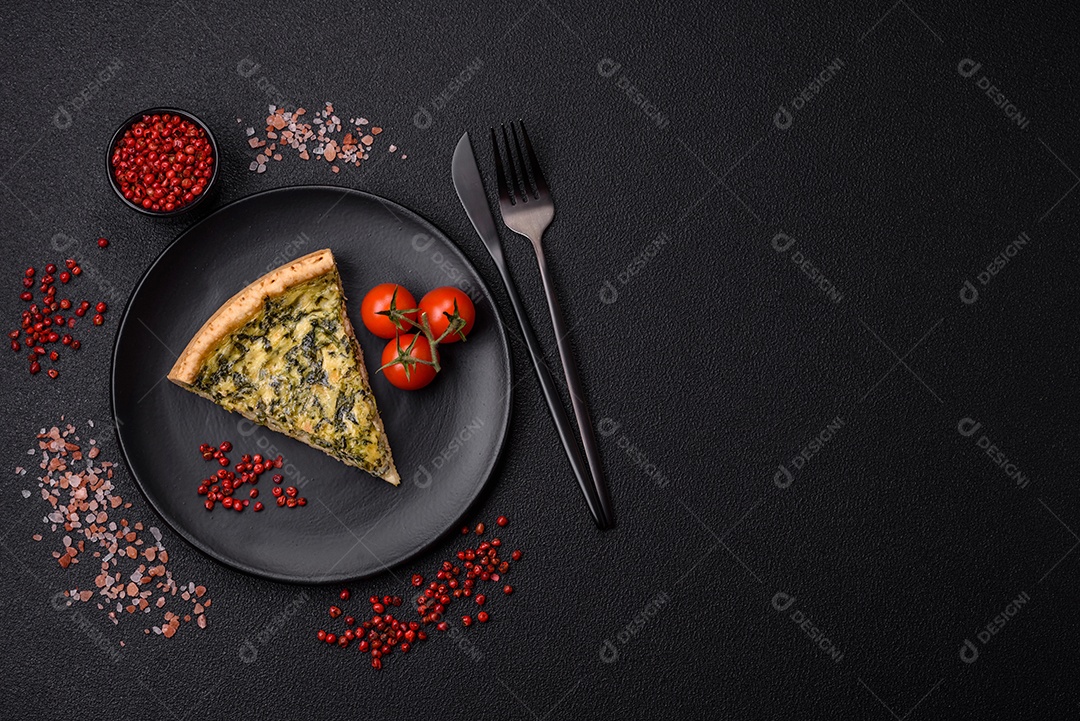 Deliciosa quiche crocante cortada em fatias com queijo, brócolis, tomate, sal, especiarias e ervas sobre um fundo escuro de concreto