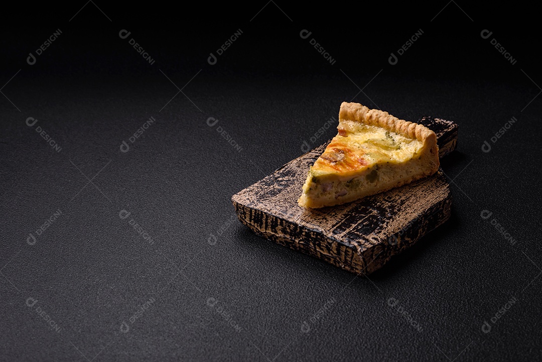 Deliciosa quiche crocante cortada em fatias com queijo, brócolis, tomate, sal, especiarias e ervas sobre um fundo escuro de concreto