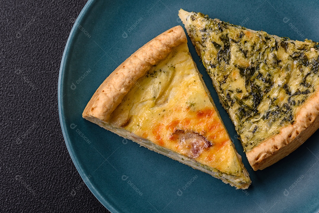 Deliciosa quiche crocante cortada em fatias com queijo, brócolis, tomate, sal, especiarias e ervas sobre um fundo escuro de concreto