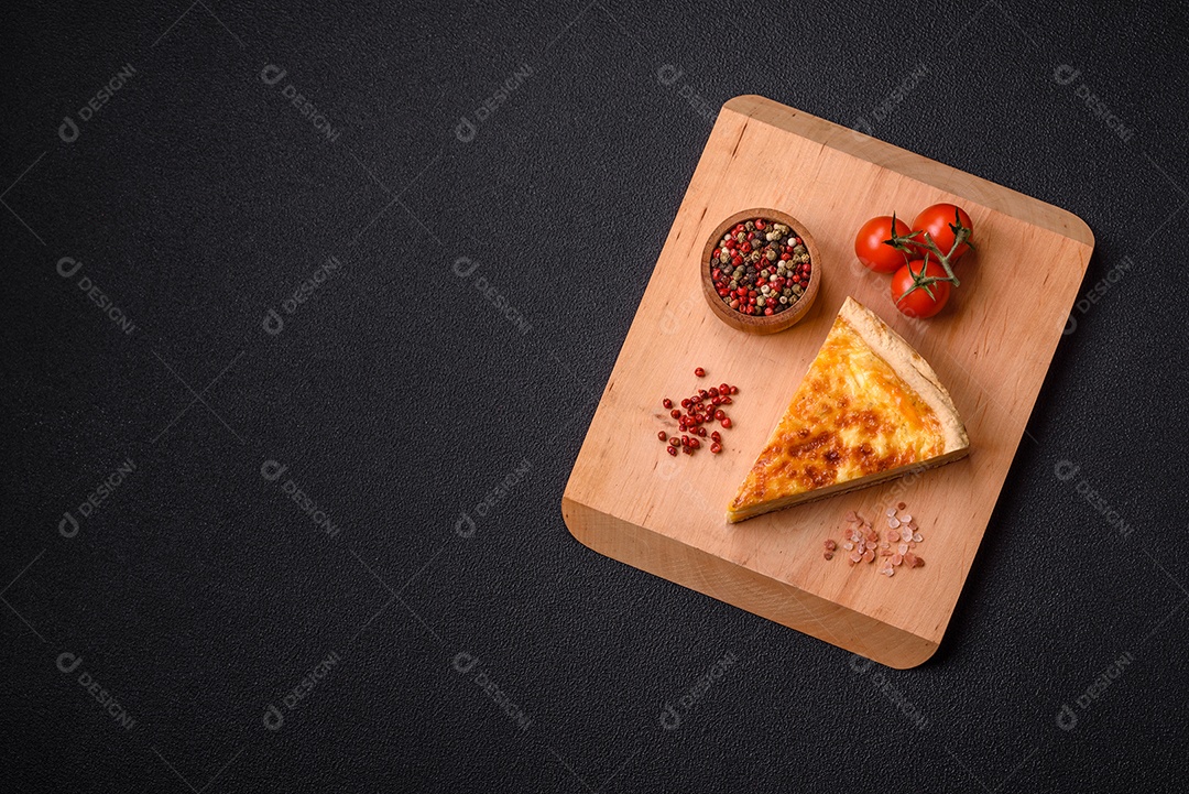 Deliciosa quiche crocante cortada em fatias com queijo, brócolis, tomate, sal, especiarias e ervas sobre um fundo escuro de concreto