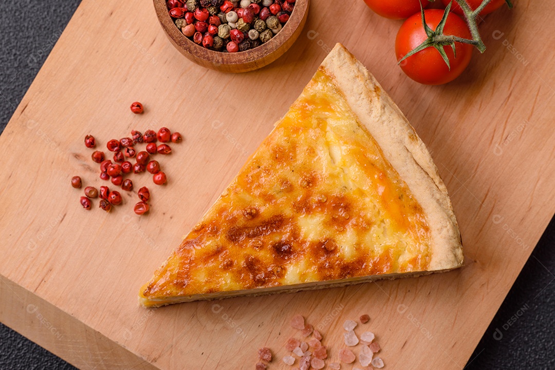 Deliciosa quiche crocante cortada em fatias com queijo, brócolis, tomate, sal, especiarias e ervas sobre um fundo escuro de concreto