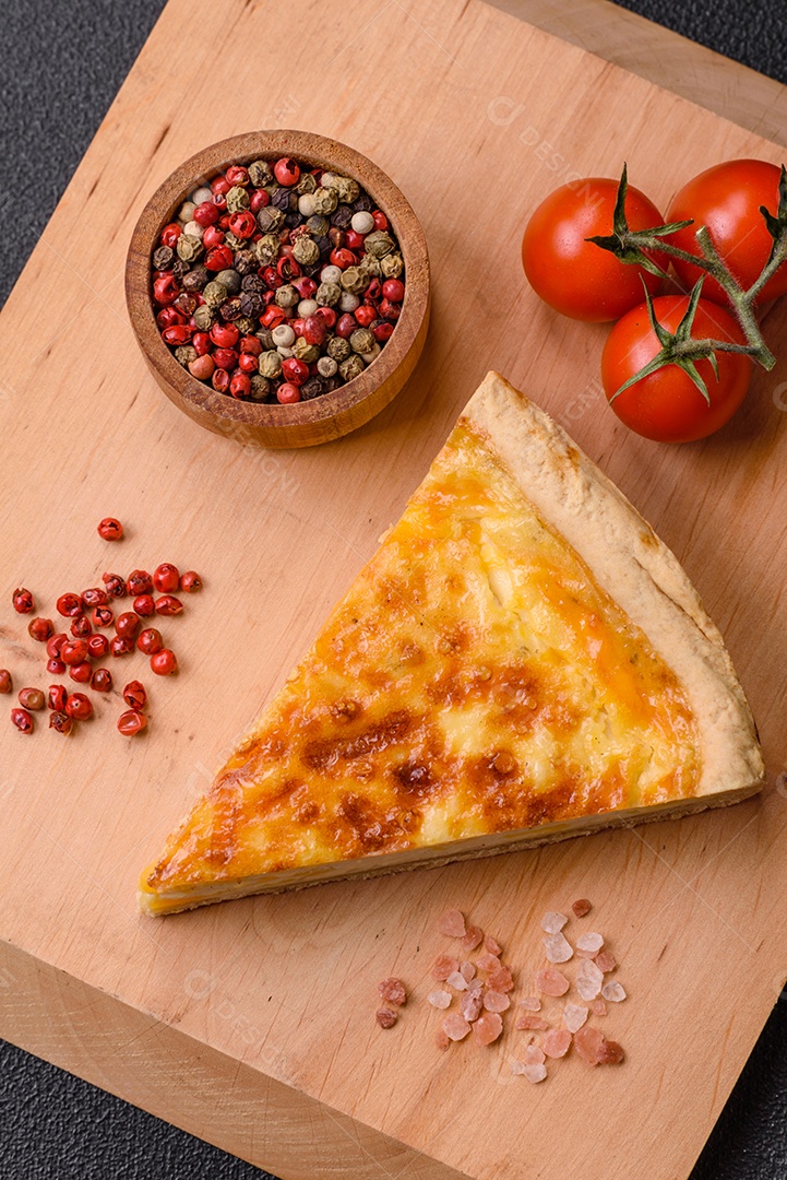 Deliciosa quiche crocante cortada em fatias com queijo, brócolis, tomate, sal, especiarias e ervas sobre um fundo escuro de concreto