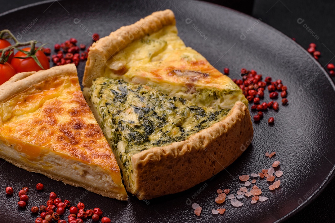 Deliciosa quiche crocante cortada em fatias com queijo, brócolis, tomate, sal, especiarias e ervas sobre um fundo escuro de concreto