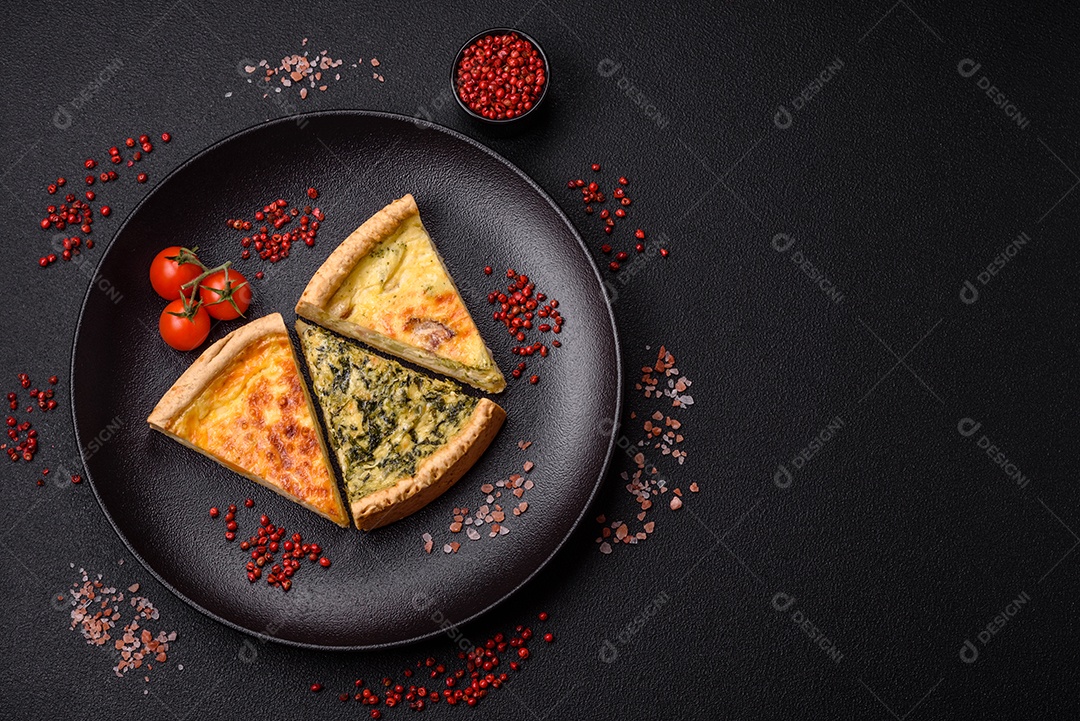 Deliciosa quiche crocante cortada em fatias com queijo, brócolis, tomate, sal, especiarias e ervas sobre um fundo escuro de concreto