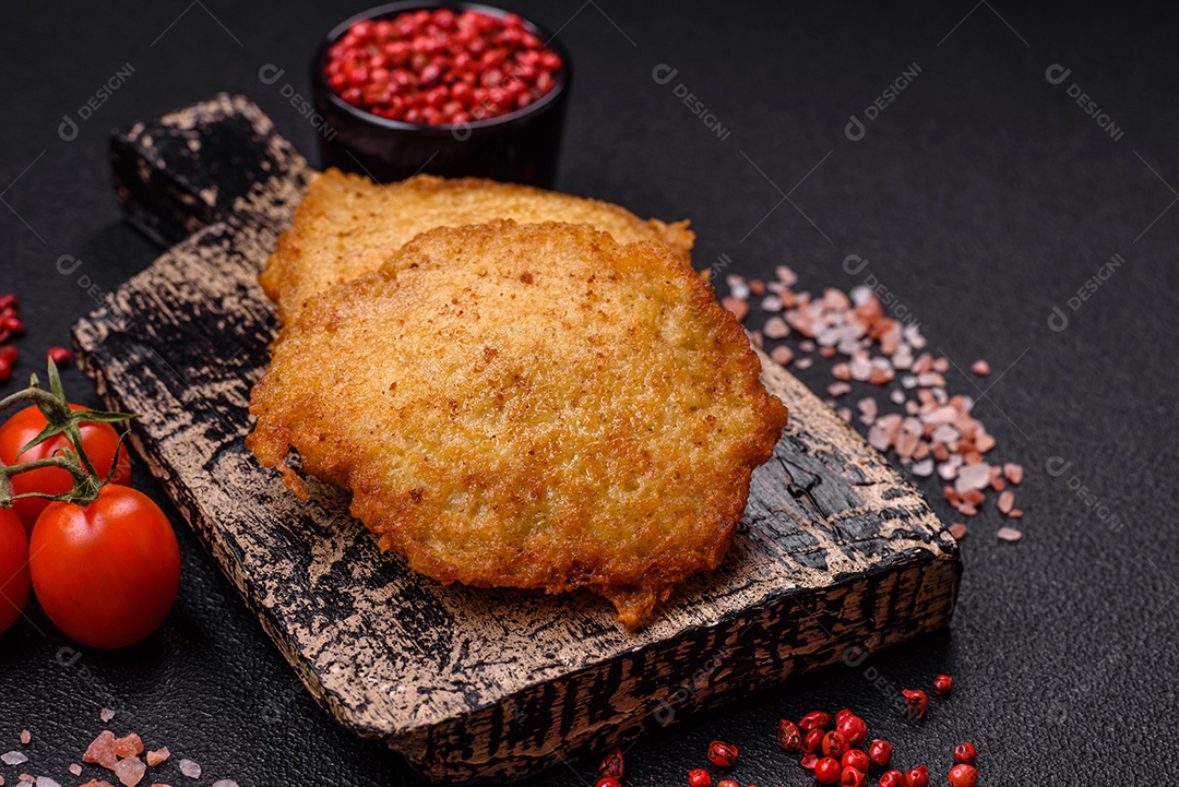 Deliciosas panquecas crocantes feitas de batatas, carne, cenouras, cebolas com sal, especiarias e ervas sobre um fundo escuro de concreto