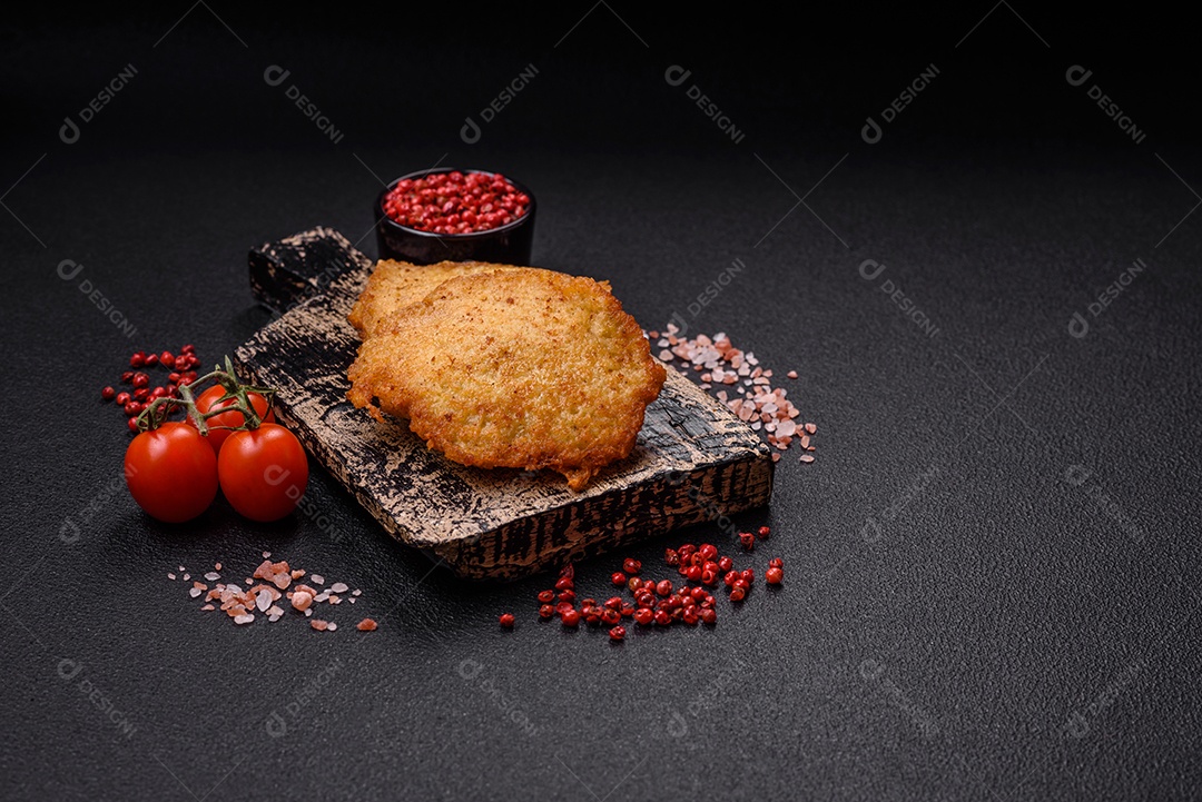 Deliciosas panquecas crocantes feitas de batatas, carne, cenouras, cebolas com sal, especiarias e ervas sobre um fundo escuro de concreto