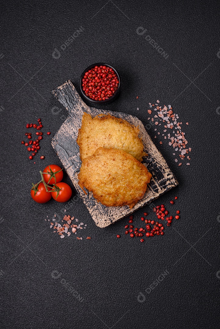 Deliciosas panquecas crocantes feitas de batatas, carne, cenouras, cebolas com sal, especiarias e ervas sobre um fundo escuro de concreto